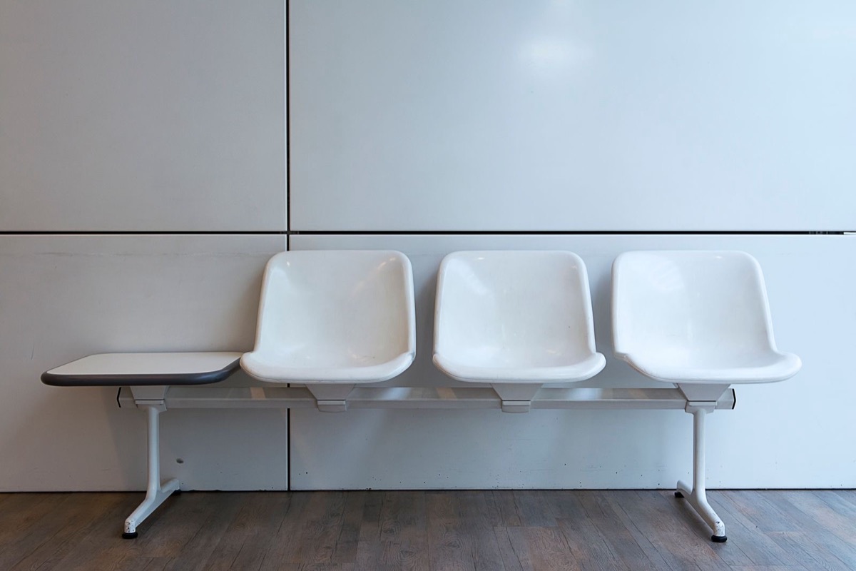 A row of white waiting-room seats against a wall
