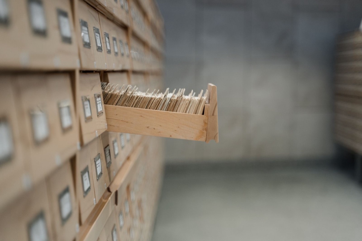 An open drawer of index cards in a wall of archive drawers