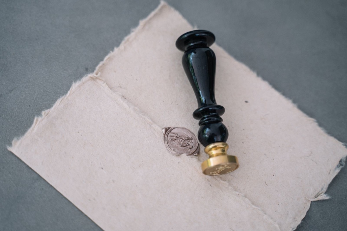 A sheet of handmade paper closed with a wax seal, the seal stamp beside it