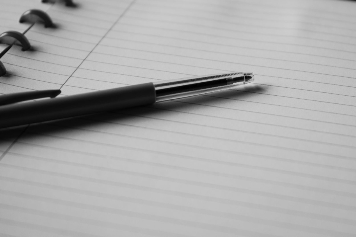 A pen on the ruled pages of a spiral notebook