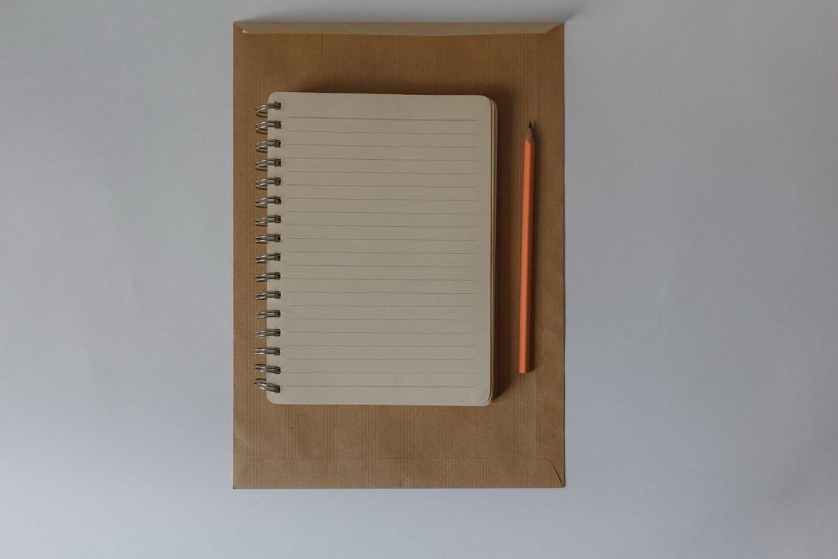 A lined notebook and a pencil on a kraft envelope