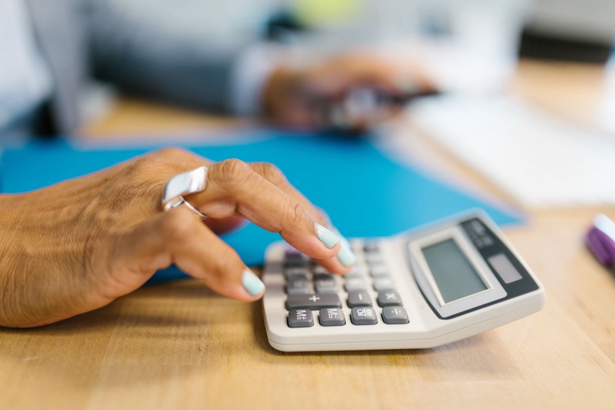A hand using a calculator beside a blue folder