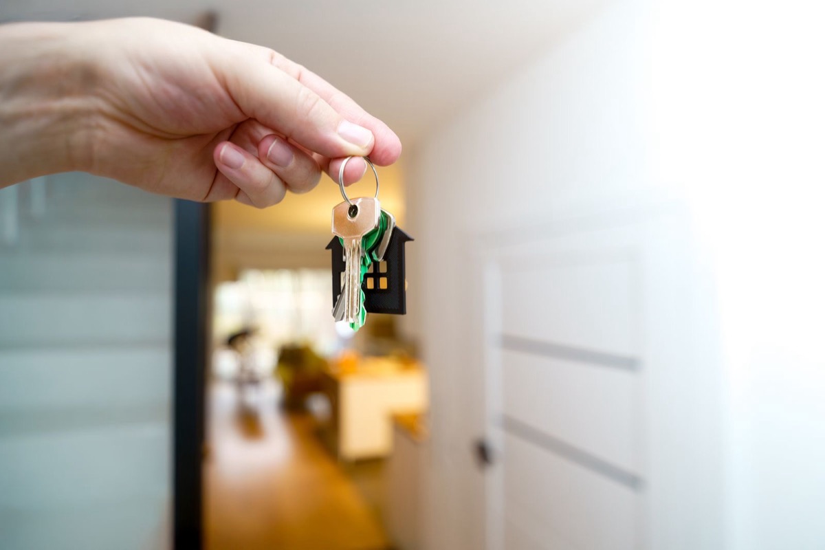 A hand holding house keys in a bright flat