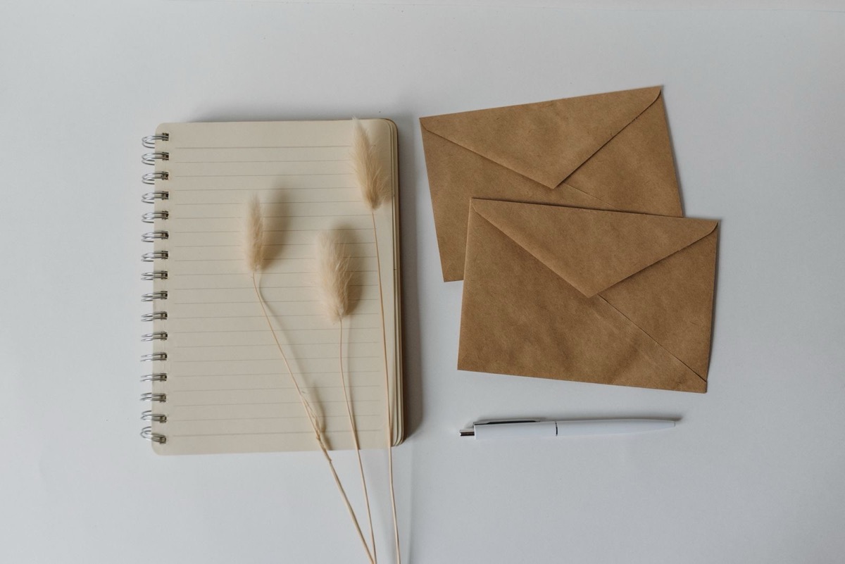 Kraft envelopes beside a spiral notebook and a pen